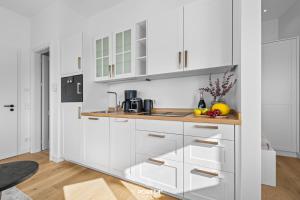 - une cuisine blanche avec des placards blancs et des fruits sur le comptoir dans l'établissement Ferienwohnung Leichte Brise Westerland auf Sylt, à Westerland