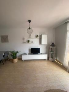 a white living room with a tv and a tiled floor at Light House in Corralejo