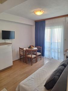 a room with a bed and a table and a television at Apartments Dalmacija in Podstrana