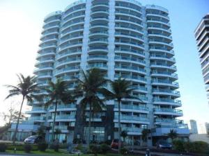 Un gran edificio con palmeras delante. en Flat Residencial Praia da Barra, Piscina e Sauna - Frente Mar D68508, en Río de Janeiro