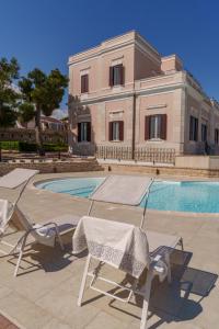 a pair of chairs and a pool in front of a building at Villa Emy Boutique Bed & Breakfast in Bisceglie