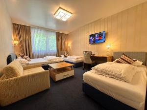 a hotel room with two beds and a tv at Hotel Austria Self Checkin in Gablitz