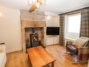 a living room with a fireplace and a tv at Bank Cottage in Bradwell