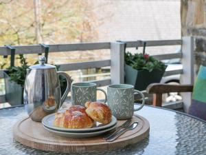 a table with a plate of pastries and coffee cups at Bank Cottage in Bradwell