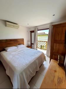 Residência em condom, 1 ou 2 suítes, vista para o mar, Praia do Curral, Ilhabela في إلهابيلا: غرفة نوم بسرير كبير ونافذة كبيرة