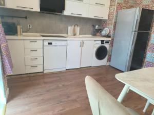 a kitchen with white cabinets and a washer and dryer at Home away home in Mekhrably