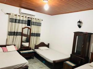 a small room with two beds and a mirror at Singhe Holiday Bungalow in Nikawatawana