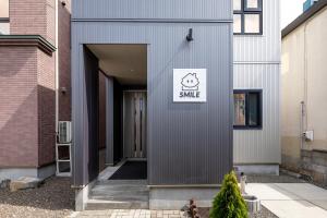a grey house with a smile sign on the side of it at The SMILE in Sapporo