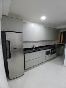 una cucina con mobili bianchi e un frigorifero in acciaio inossidabile di Apartamento Beira-mar orla sul a Ilhéus Altre 12 foto