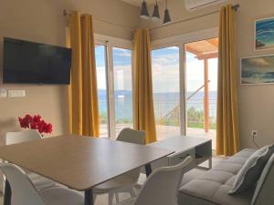 a dining room with a table and chairs and a large window at Villa Banana in Lourdata