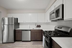 a kitchen with white cabinets and a stainless steel refrigerator at Charming Rochester Retreat Cozy & Stylish Stay in Rochester Hills