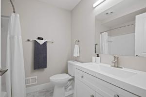 a white bathroom with a toilet and a sink at Charming Rochester Retreat Cozy & Stylish Stay in Rochester Hills