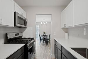 a white kitchen with a stove and a table at Cozy Stay Modern Comfort in the City in Rochester Hills