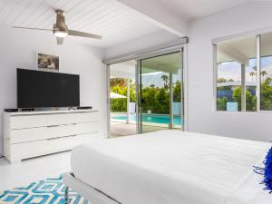 a white bedroom with a bed and a tv at As seen on HGTV Desert Flippers The Pink Door in Palm Springs