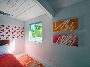 a bedroom with two paintings on the wall and a window at As seen on HGTV Desert Flippers The Pink Door in Palm Springs +41 photos