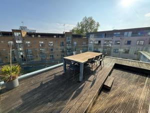 a wooden table and chairs on the roof of a building at Penthouse on the Grange in London
