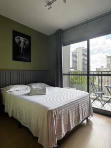 a bedroom with a large bed and a large window at Studio Avenida Paulista - Nex One Consolação in Sao Paulo