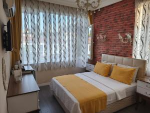 a bedroom with a brick wall and a bed with yellow pillows at Ozmen Hotel Old Town Kaleiçi in Antalya