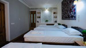 a room with three beds with white sheets at MUSLIMA HOTEL Boutique in Bukhara