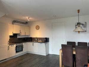 une cuisine avec des placards blancs, une table et une horloge dans l'établissement Nieuw gebouwd appartement op paarden bedrijf, à Buitenpost 10 autres photos