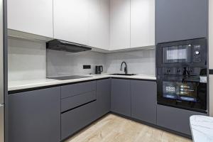 a kitchen with white cabinets and black appliances at Vivenda in Astana