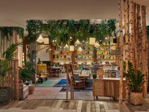 a restaurant with tables and chairs and plants at Treehouse Hotel Manchester in Manchester