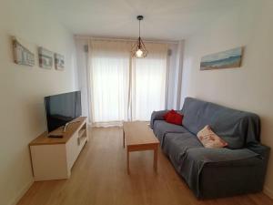 a living room with a blue couch and a television at Marina3 - Playa de Daimús - Ganador Traveller Awards 2026 in Daimuz