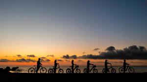 a group of people riding bikes on the beach at sunset at Case Vacanza Loria in Castelluzzo