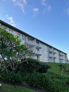 an apartment building with a tree in front of it at Jakaranda 22 apartment, Uvongo in Uvongo Beach