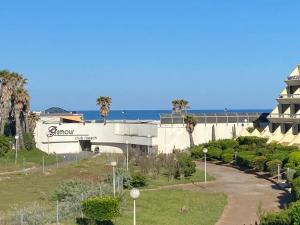 a building with palm trees and the ocean in the background at Cap sur le Paradis in Cap d'Agde