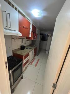 a small kitchen with red cabinets and a stove at Apartamento próximo a praia in Maceió