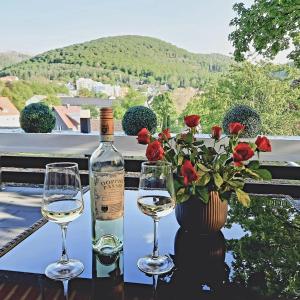 two glasses of white wine next to a vase with roses at Bergliebe 5 mit großer Terrasse, Tiefgarage & Lift in Bad Harzburg