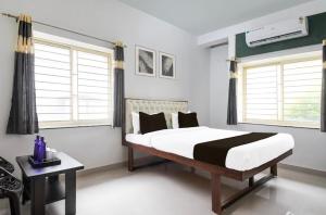 a bedroom with a large bed and two windows at Hotel Crystal INN in Bhubaneshwar