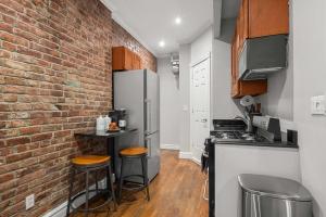 a kitchen with a brick wall and a refrigerator at Stylish Escape Modern 2BR Condo on Prince Street in New York