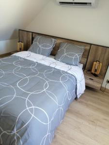 una camera da letto con un letto con un piumone grigio e bianco di Agréable maison au cœur d'un petit village a Saint-Genou