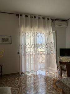 a white curtain in a room with a window at Casa Puglia in Giardini Naxos