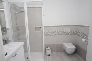 a white bathroom with a shower and a toilet at Maison Mimi apartments in Ossuccio +15 photos