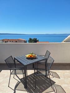 a table with chairs and a bowl of fruit on a balcony at Apartments Dalmacija in Podstrana