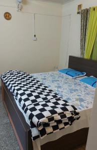 ムスーリーにあるHills Homestayのベッド(上にチェック入りの毛布付)