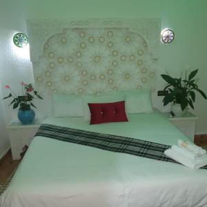 a bedroom with a white bed with red pillows at Riad golf stinia in Meknès