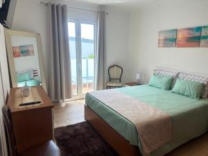 a bedroom with a bed and a table and a window at Gori House in Madalena do Mar