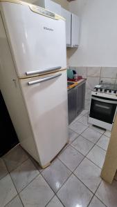 Una cocina con un refrigerador blanco y una estufa. en Duplex dos Anjos, en Arraial do Cabo