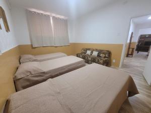 a small room with two beds and a couch at Apto na Rua Principal - Centro in Serra Negra