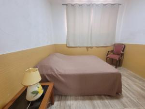 a bedroom with a bed and a table with a lamp at Apto na Rua Principal - Centro in Serra Negra +6 photos