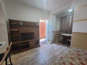 a living room with a television and a table at Apto na Rua Principal - Centro in Serra Negra