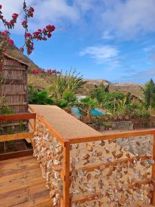 a wooden deck with a stone wall and a view at Bangaló Buzio Relax in Portal