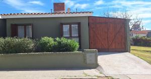 a house with a wooden gate and a driveway at La casa, alquiler temporario - casa completa con cochera y patio- parrilla in Villa Mercedes