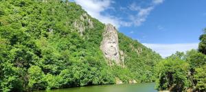 a river in front of a mountain with trees at Apartament Alexandra in Orşova