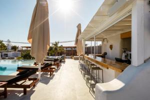 an outdoor bar with tables and chairs next to a pool at Irene's Residence in Mikonos