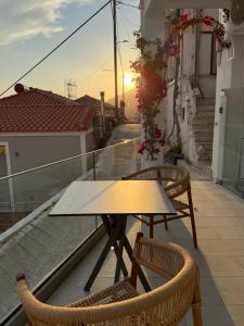 a table and chairs on a balcony with the sunset at Michalelis cave & loft in Plomari